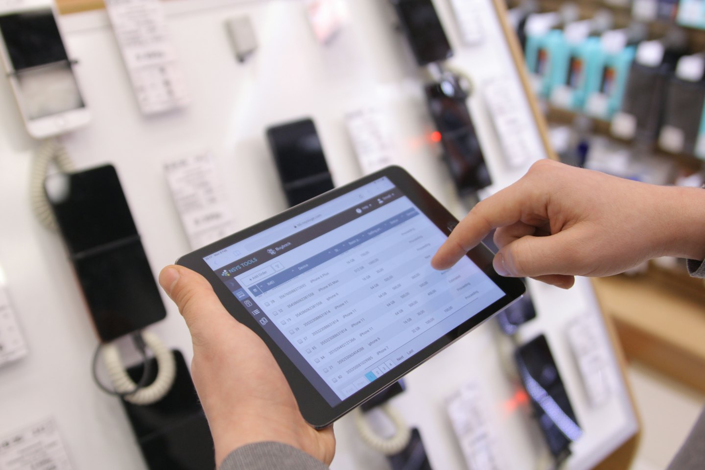 Manos gestionando inventario de tienda en pantalla de tableta.