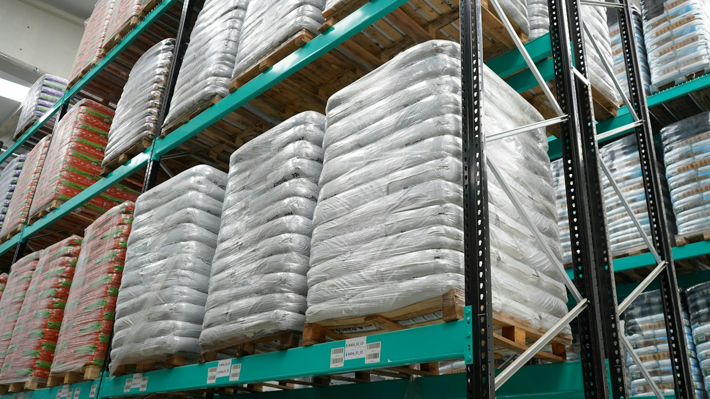 Almacén industrial lleno de mercancía en estanterías sobre palés.